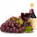 A bunch of red grapes, a glass of red wine and a bottle of red wine.