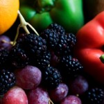 A close up shot of grapes, peppers and raspberries.