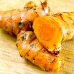 2 fresh pieces of turmeric on a wooden board.