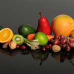A selection of fruits and vegetables on a reflective black background.