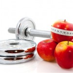 A set of dumbbells next to a pile of apples wrapped in a tape measure.