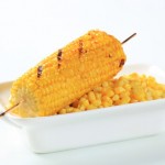 A bowl of corn topped with one piece of corn on the cob.
