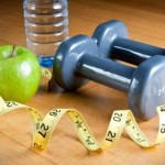 A selection of apples, dumbbells, water and a tape measure.