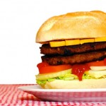A double cheeseburger on a red and white tablecloth.