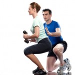 A woman performing dumbbell squats with her personal trainer.