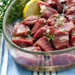 A bowl of lamb pieces in an olive oil and lemon marinade.