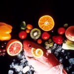 A selection of fish, fruits and vegetables on a black background.