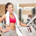 A woman in the gym standing by the exercise bikes.